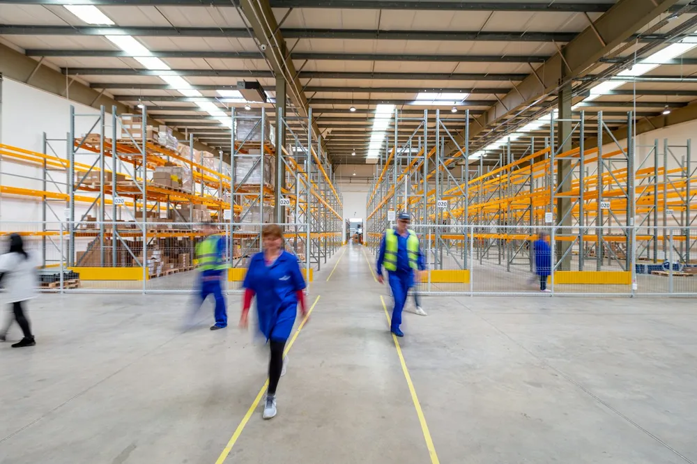 Labour hire workers in hi-vis walking through a warehouse