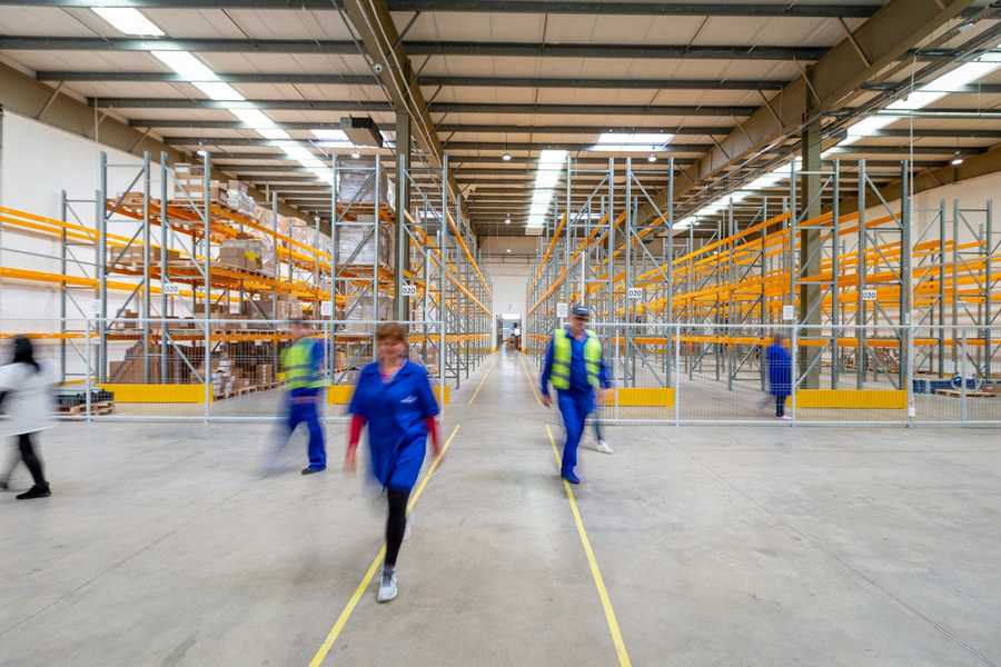 Labour hire workers in hi-vis walking through a warehouse